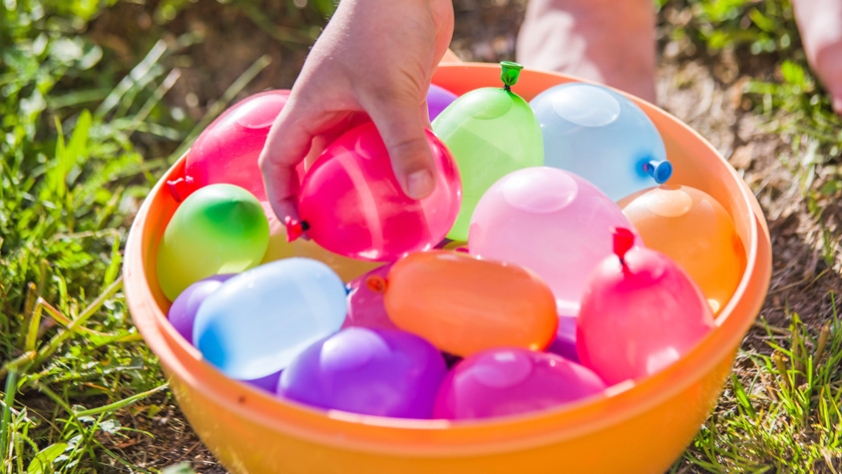 hand reaching into a bucket of water balloons