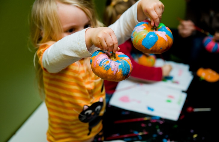 Child holding up a small painted pumpkin