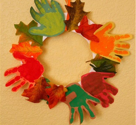 a wreath made with leaves and painted handprint tracings