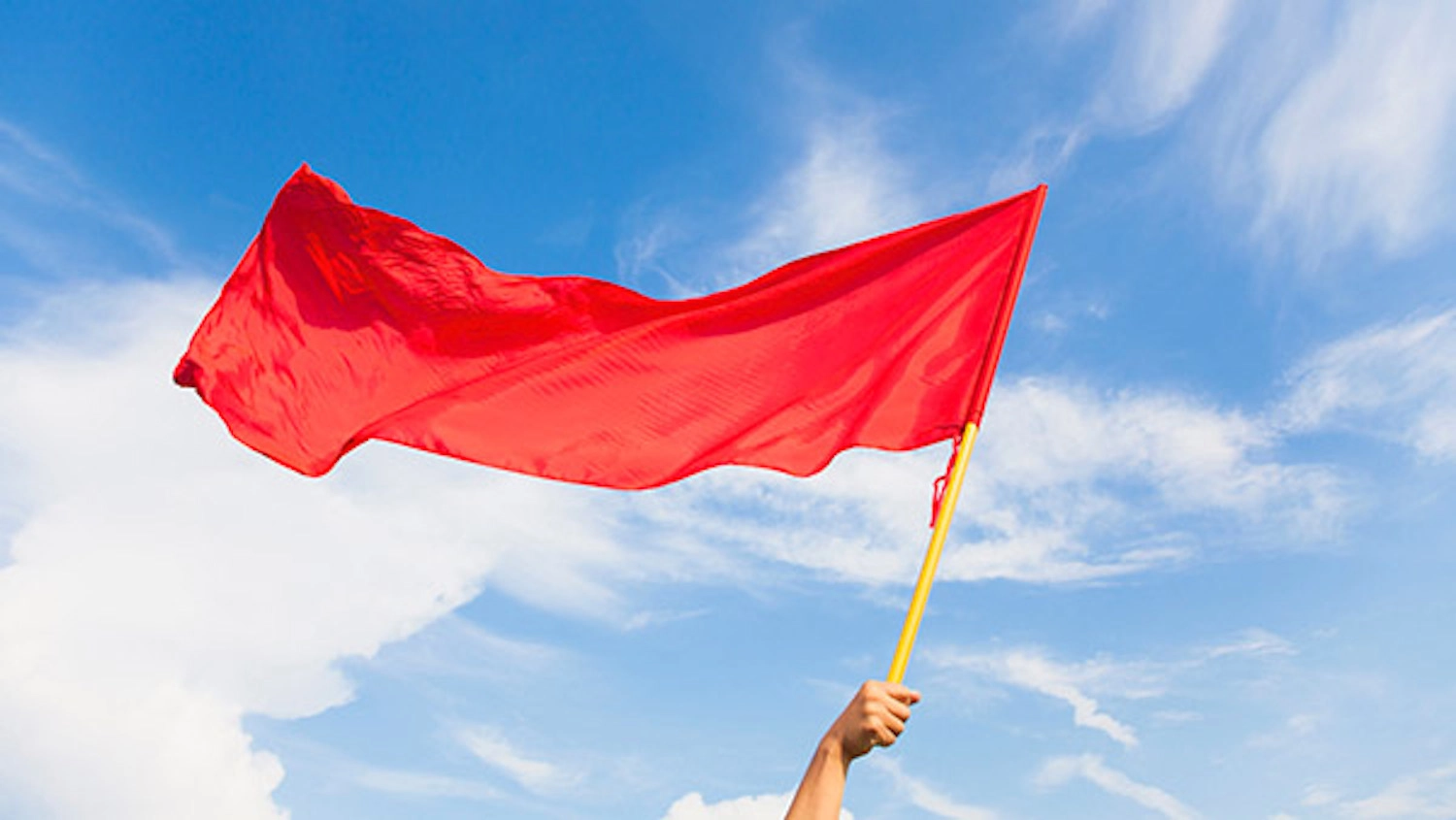 a hand holding a red flag waving in the breeze