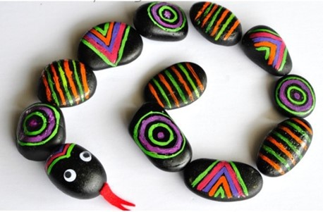 a snake made with a line of painted rocks