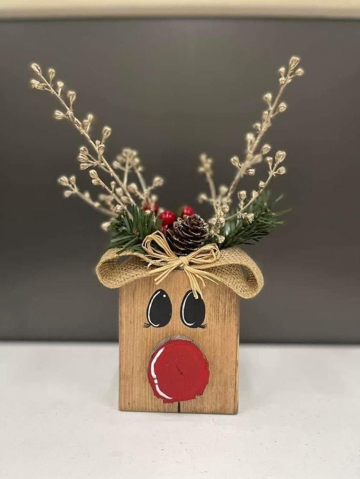 2x4 wood scrap with a painted reindeer face and floral stems for antlers