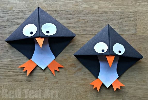 black paper folded into a square and decorated as a penguin with open corner for book page