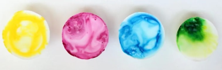 4 circular soap bars in line horizontally colored yellow, maroon, blue, and green respectively from left to right.