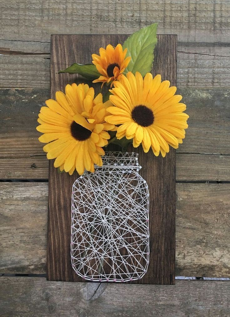 Wood plaque with string art jar and artificial yellow daisies.