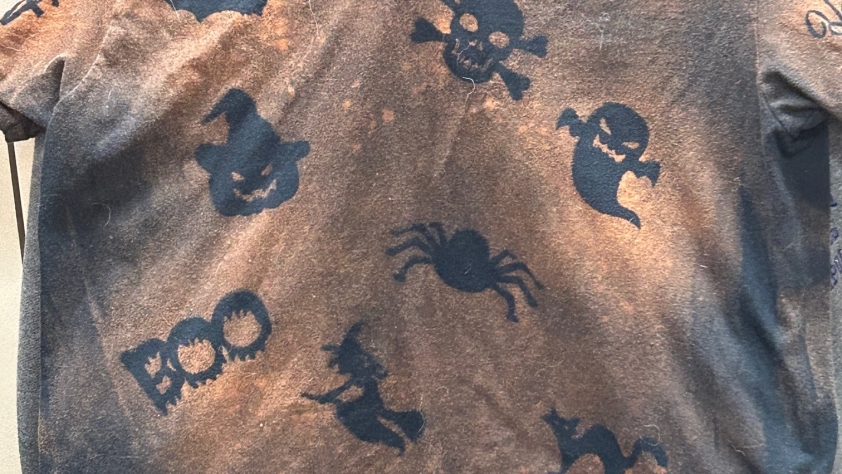 Black t-shirt with orange coloring around Halloween shapes.