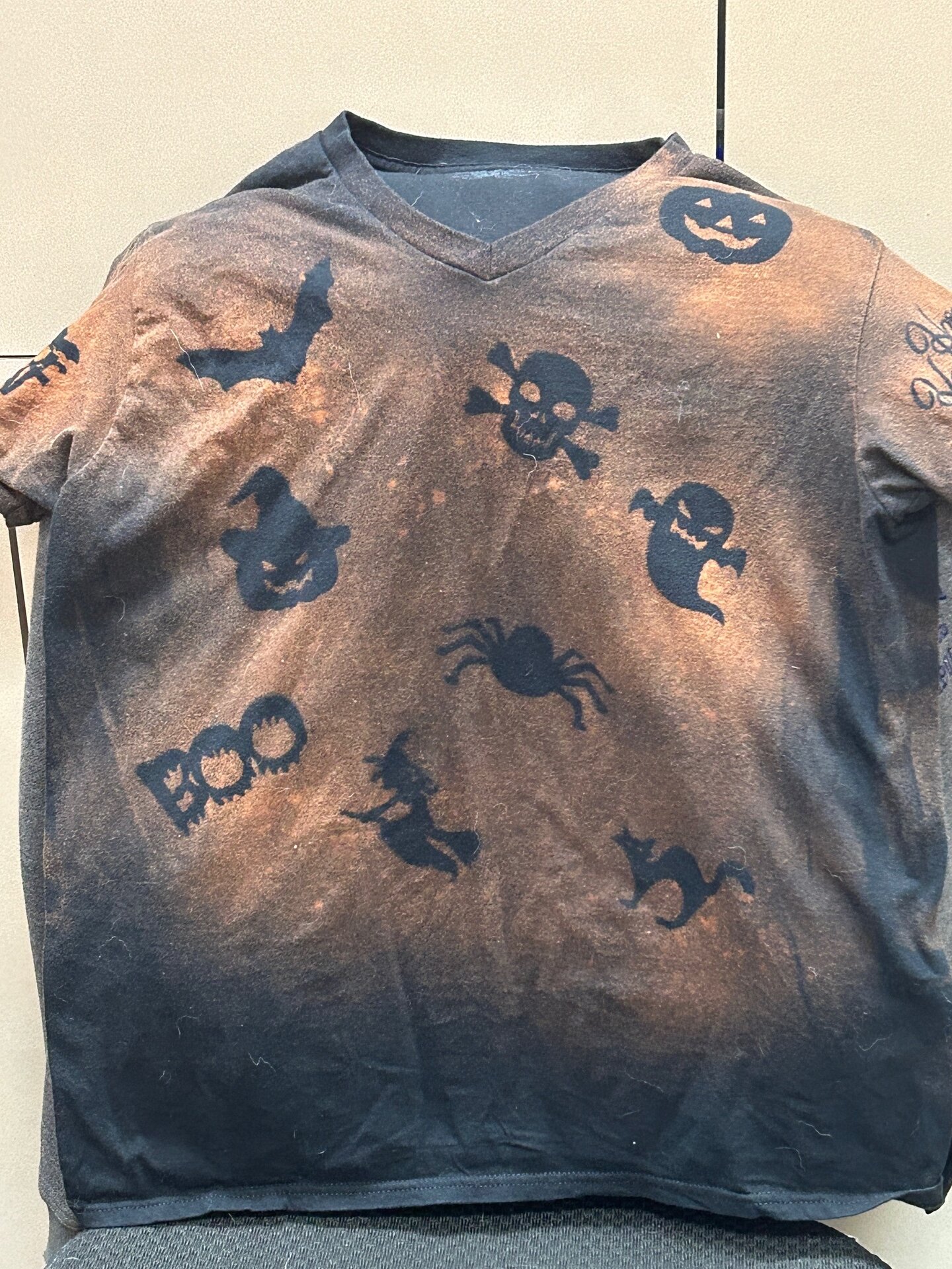 Black t-shirt with orange coloring around Halloween shapes.