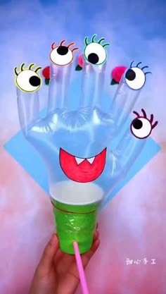 clear glove with eyes made from paper sitting on cup with straw