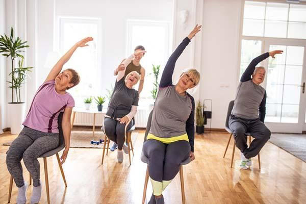 seniors and an instructor doing yoga while seated in a chair