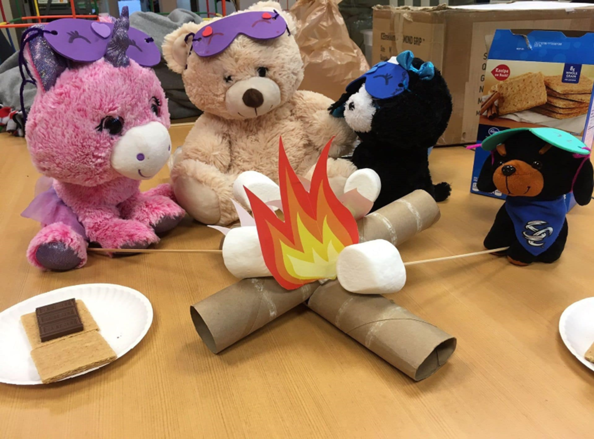 stuffed animals set up around a fake campfire and fake smores
