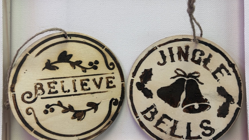 2 circular wooden ornaments with Christmas decorations on them.