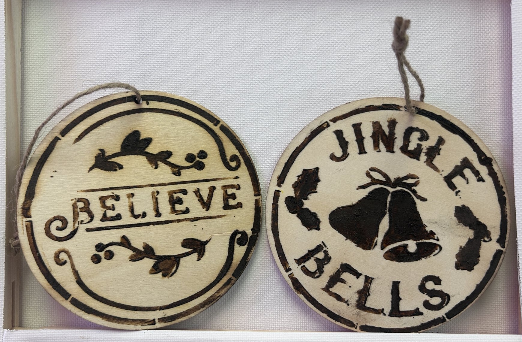 2 circular wooden ornaments with Christmas decorations on them.