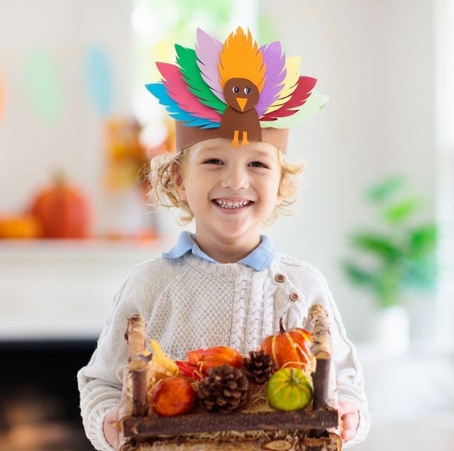 child smiling and wearing a headband made with a turkey and assorted colored feathers